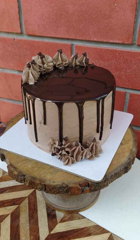 Chocolate cake with glossy ganache drip and piped chocolate rosettes